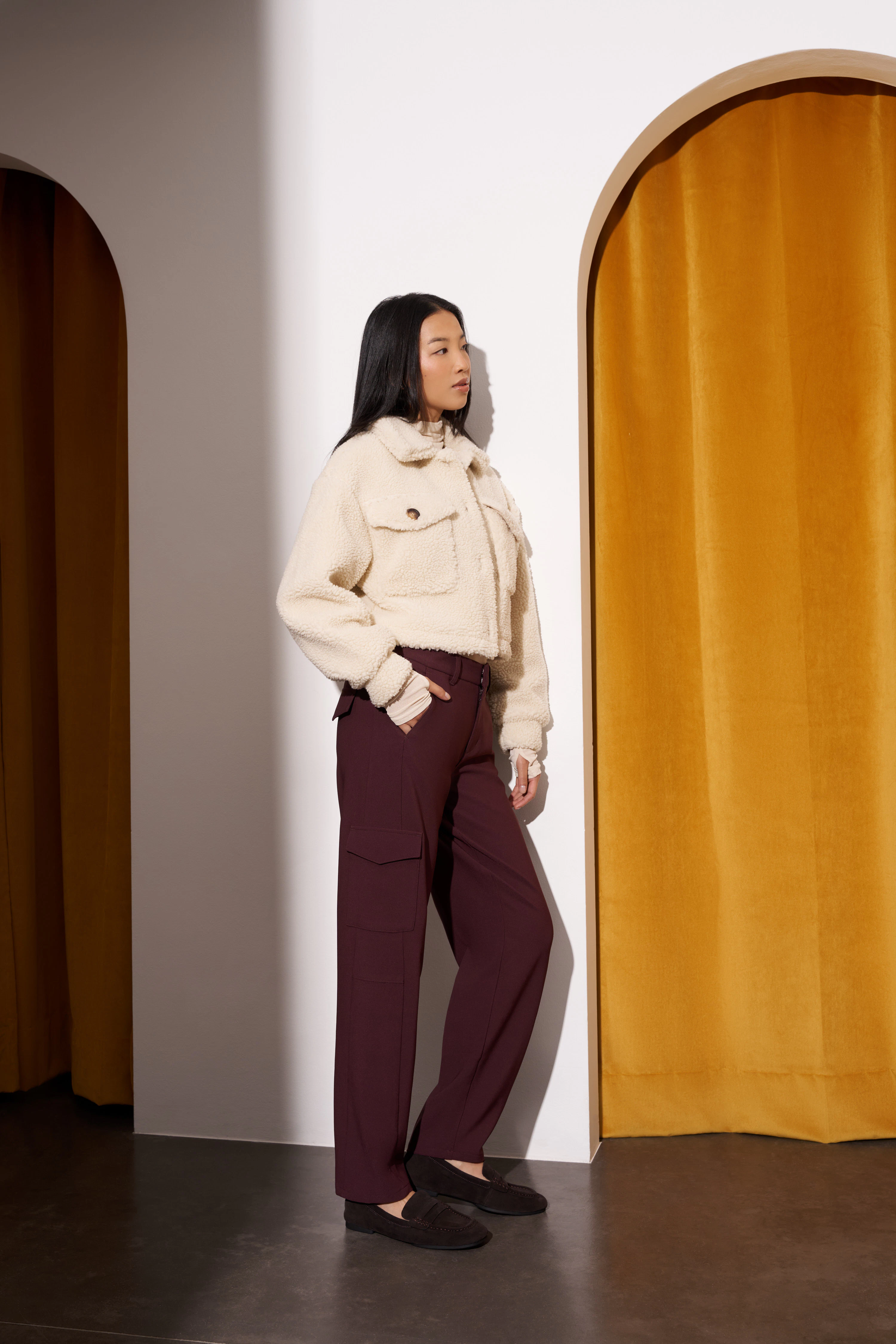 Model trägt weinrote Hose von ANGELS mit Teddyjacke und Loafern