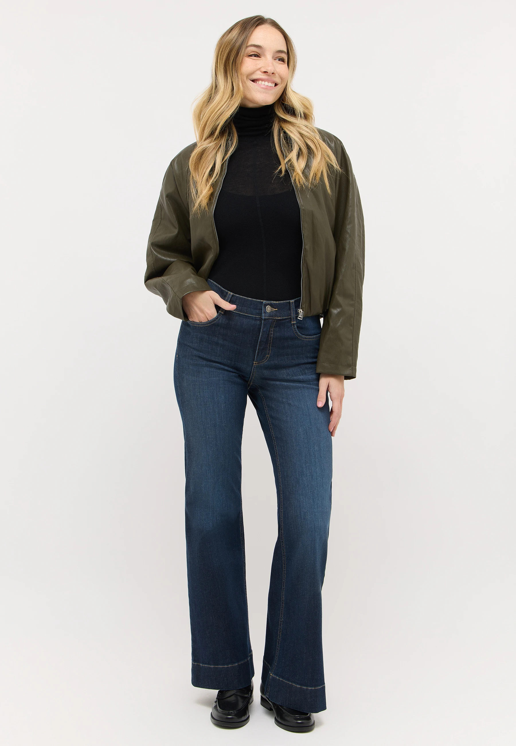 Frau in dunkelblauer ANGELS Bootcut Jeans mit dunklem Longsleeve und Jacke