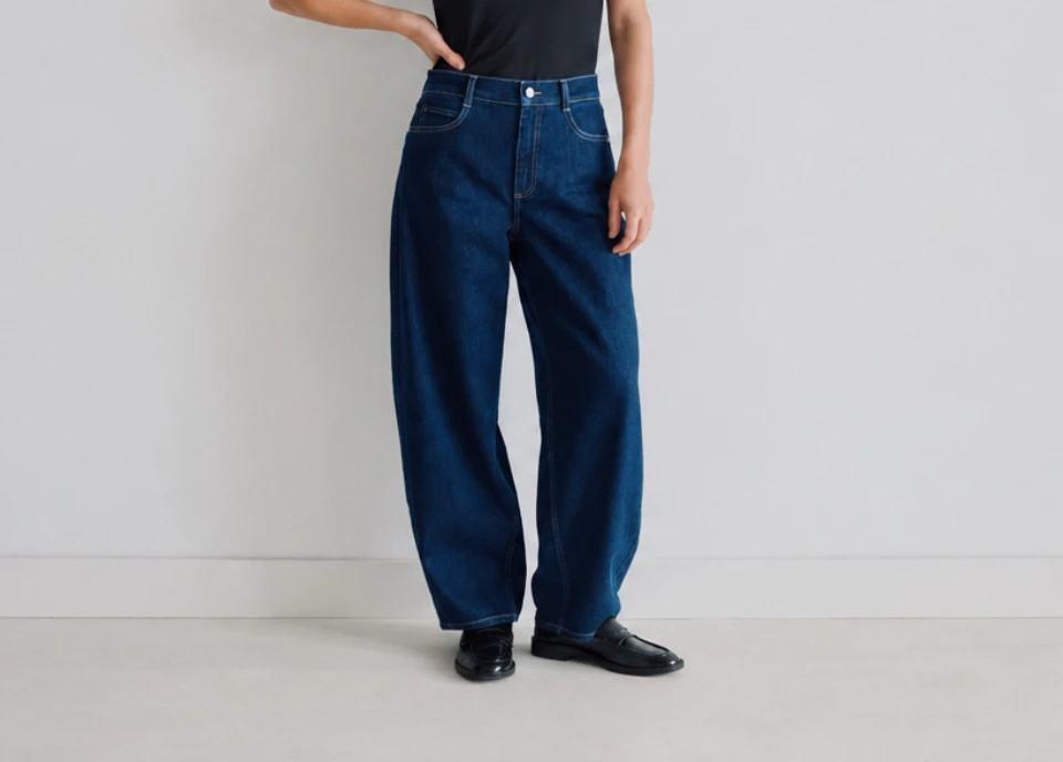 Model in dunkelblauer Wide Leg Jeans mit schwarzem Top und Loafern