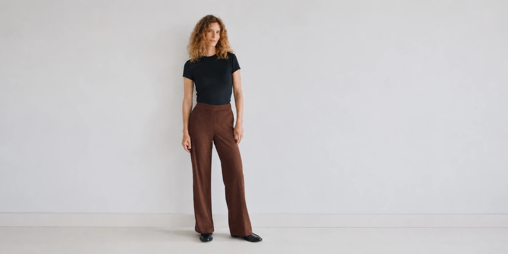 Model trägt braune ANGELS Cordhose mit weitem Bein und schwarzem Shirt