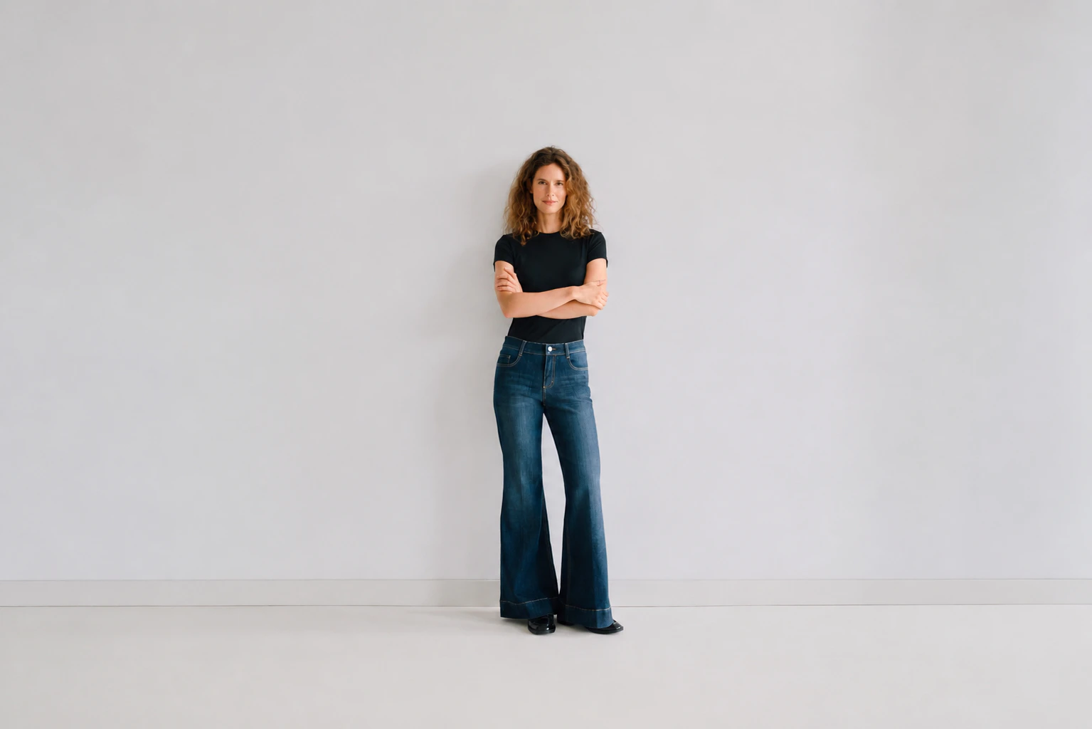 Model trägt schwarzes T-shirt und dunkle Angles Bootcut Jeans.