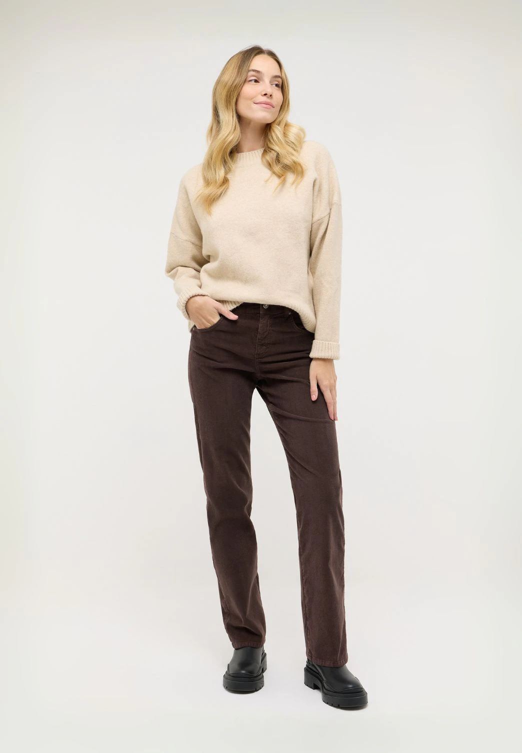 Frau trägt braune Wide Leg Cordhose für Damen mit beigem Strickpullover