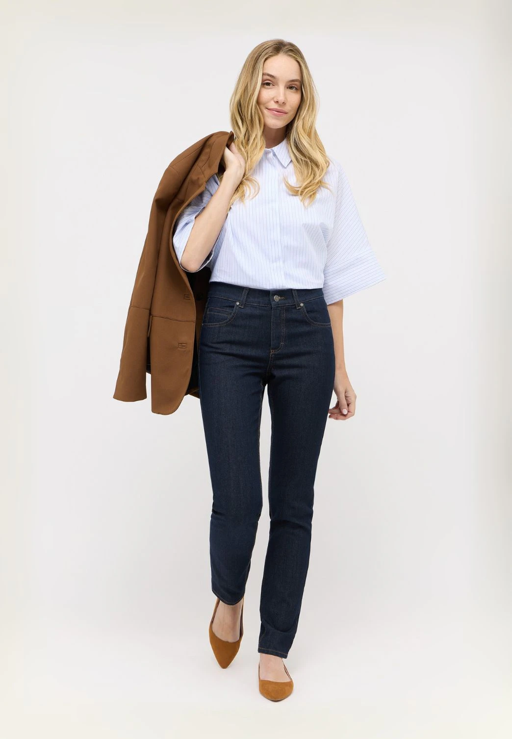 Frau in dunkler Angels Jeans mit geradem Bein, heller Bluse und Blazer
