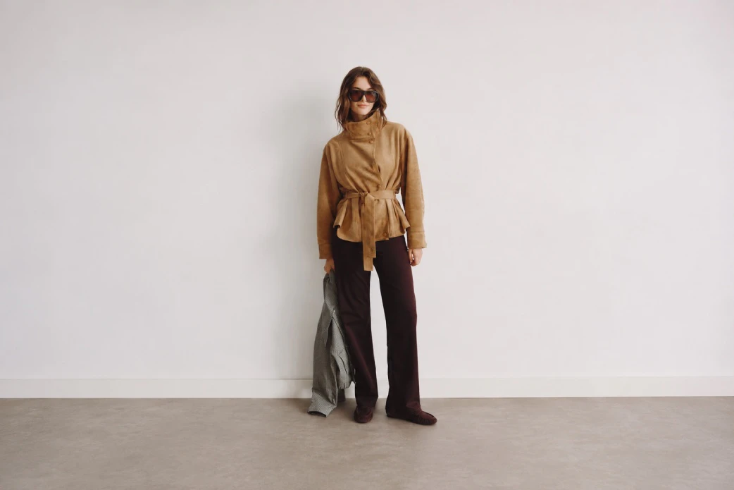 Model in dunkelbrauner Wide Leg Hose mit cognacfarbener Jacke und Gürtel