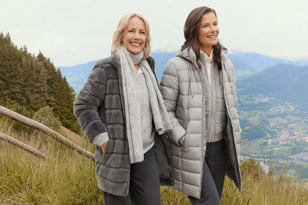 Twee vrouwen in donkere spijkerbroeken en grijze winterjassen.