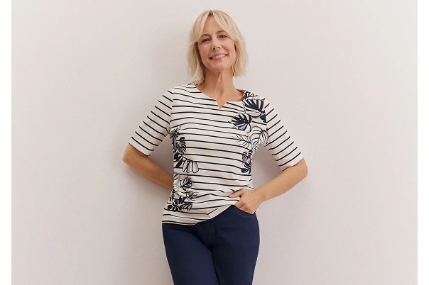 Eine Frau in blauer Caprihose und gestreiften Shirt. 