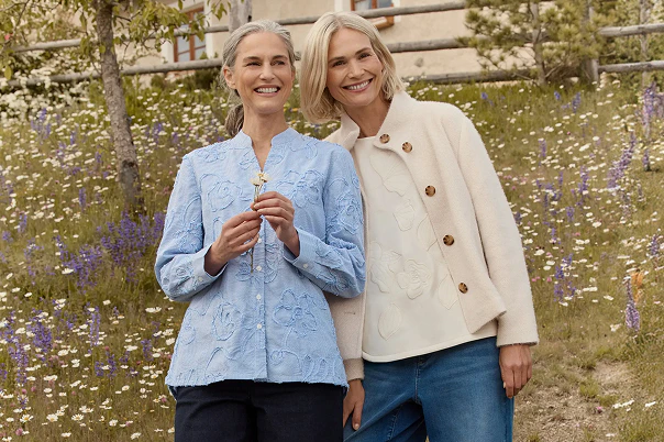 Zwei Frauen in blauer Jeans, blauer Bluse, weißem Shirt und kuscheliger Jacke. 
