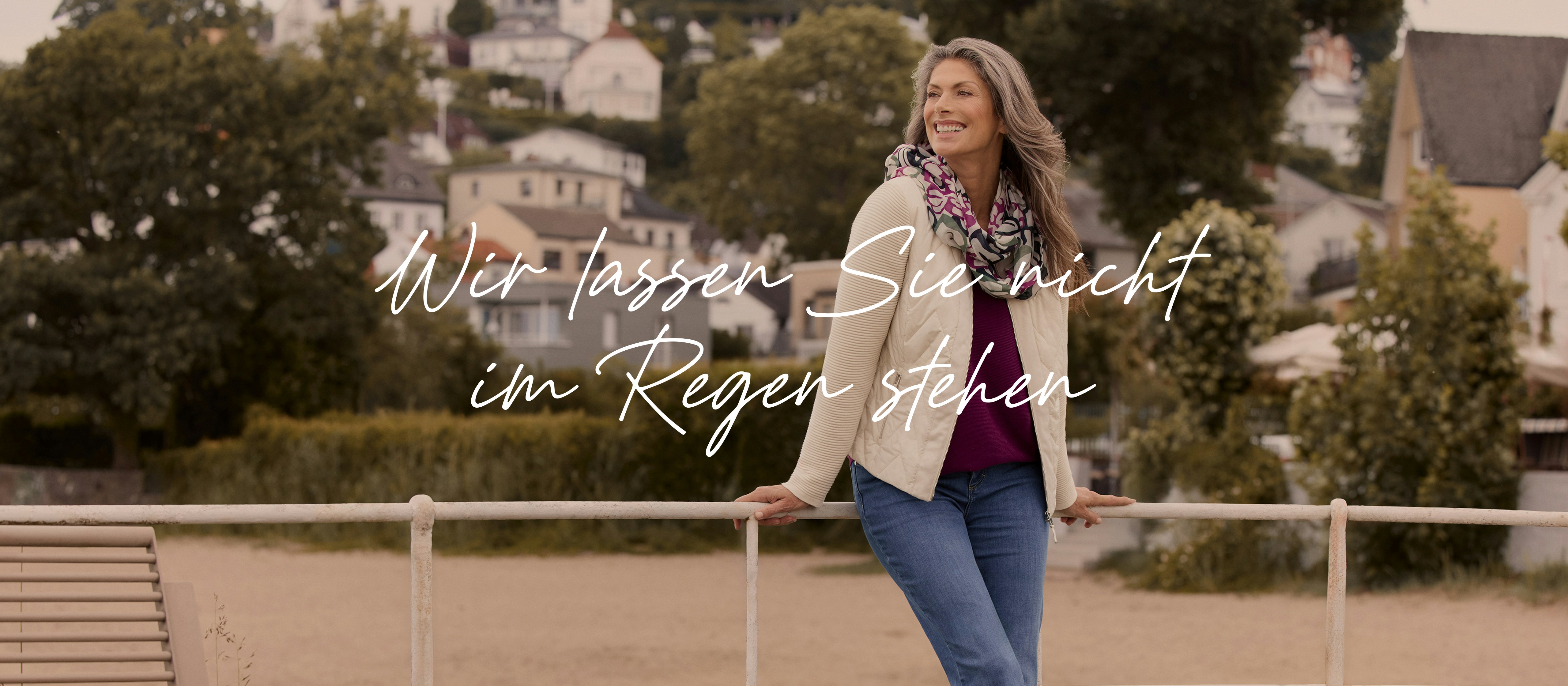 Frau in stilvoller Übergangsjacke und herbstlichem Look, steht entspannt im Freien. 