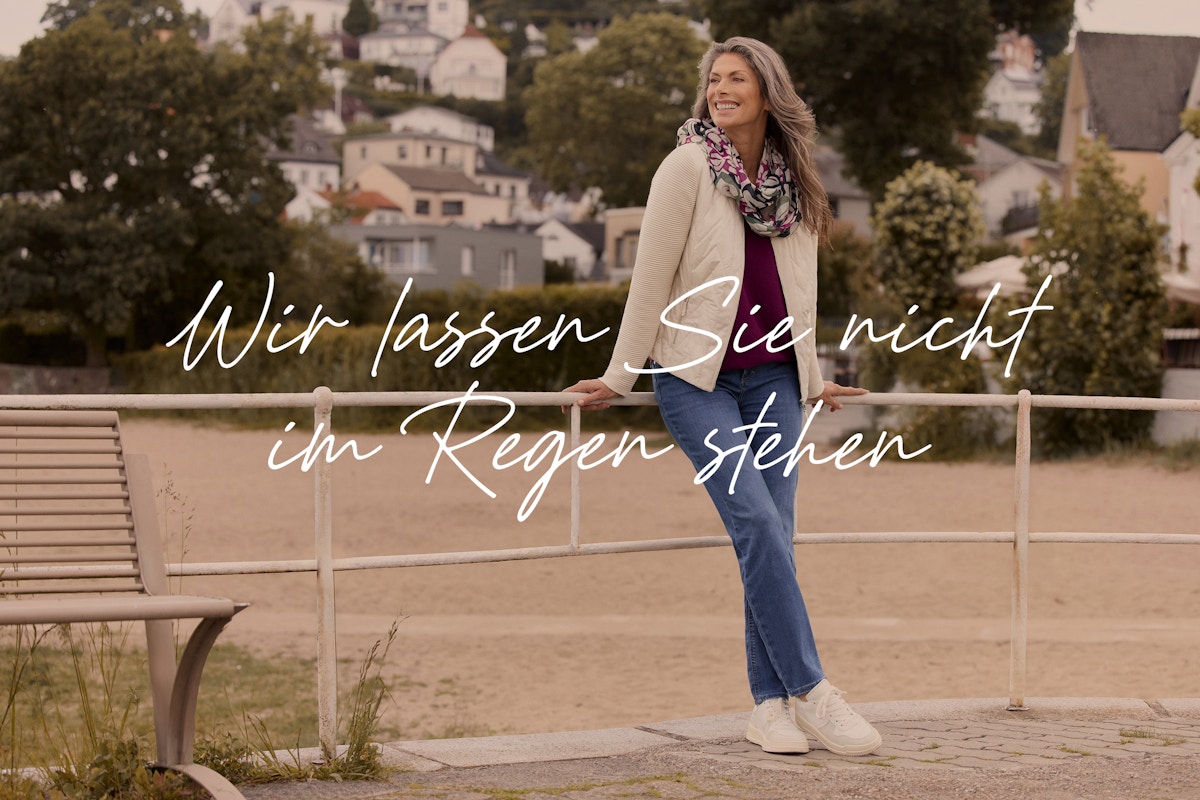 Frau in stilvoller Übergangsjacke und herbstlichem Look, steht entspannt im Freien.
