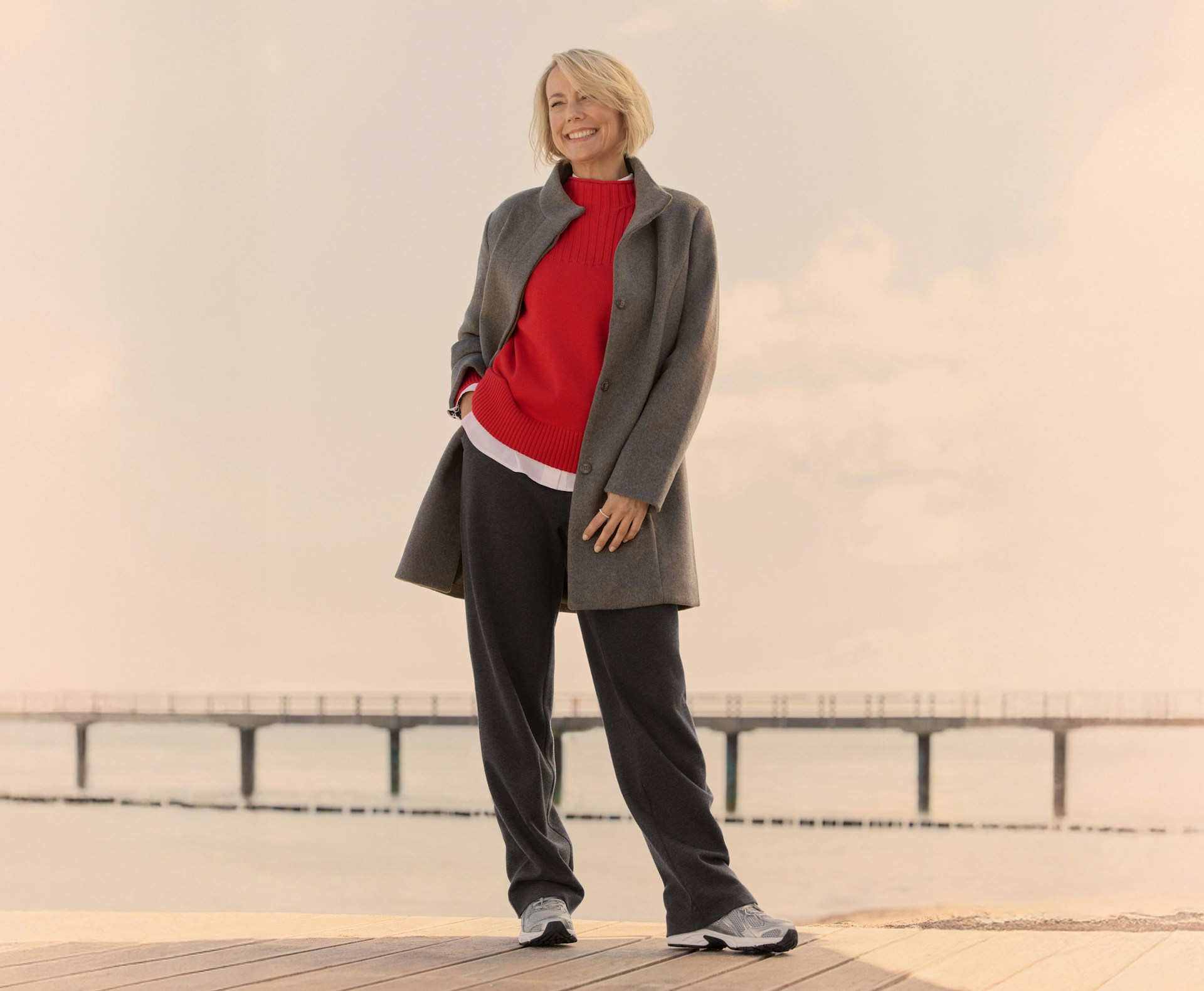 Vrouw in herfstoutfit van Bonita glimlachend op een steiger