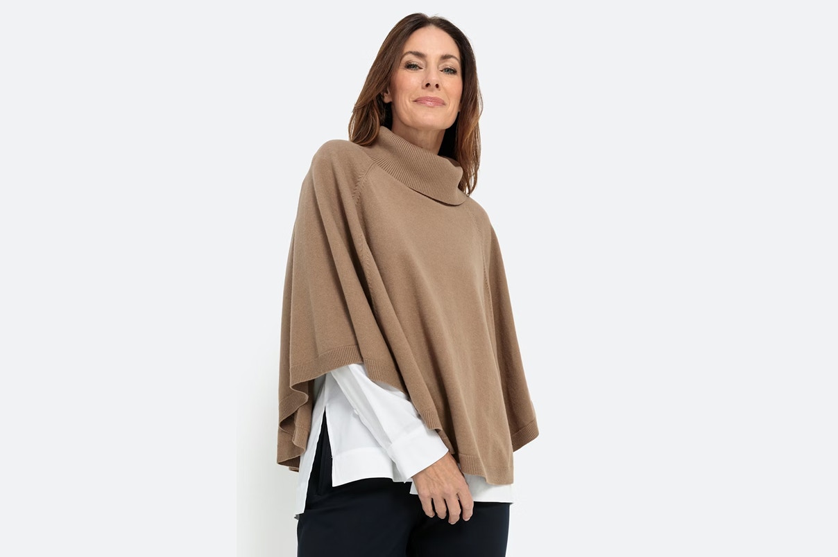 Een vrouw in een Bonita gebreide cape met een zwarte jeans.  