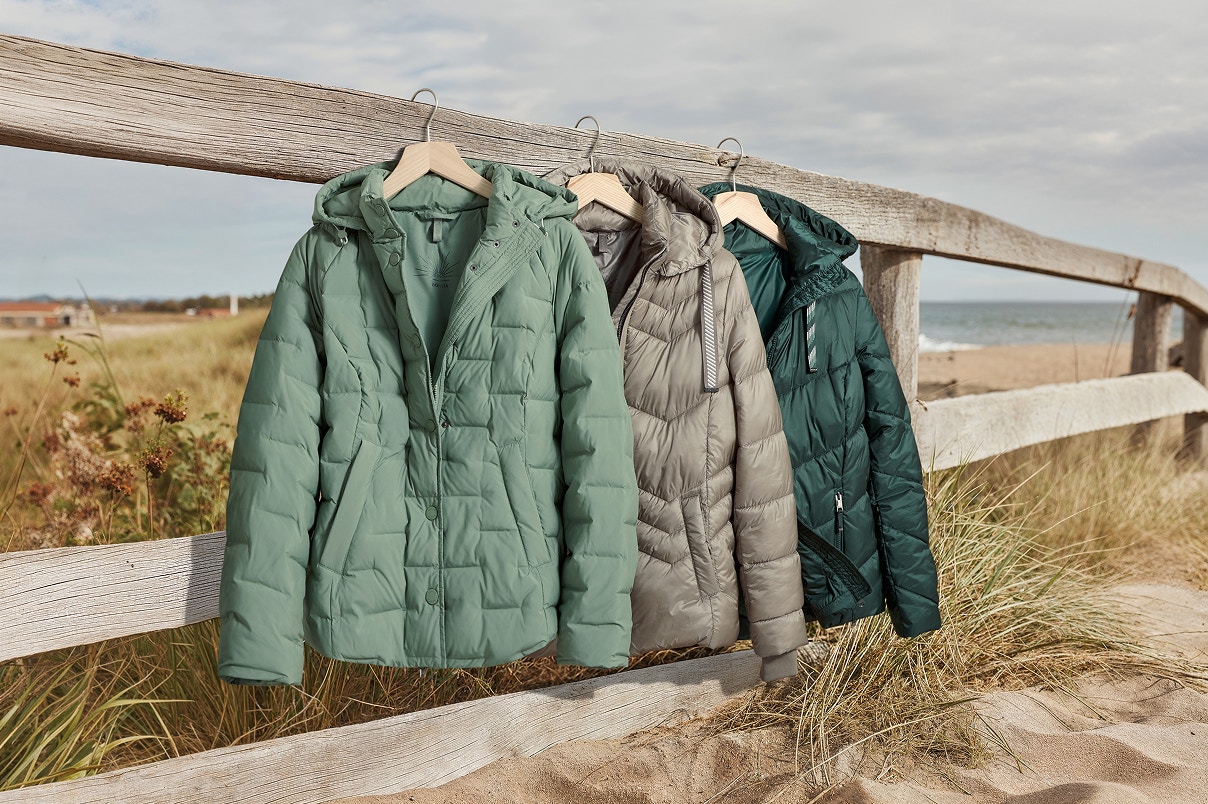 Drie Bonita winterjassen hangen aan een houten hek. 