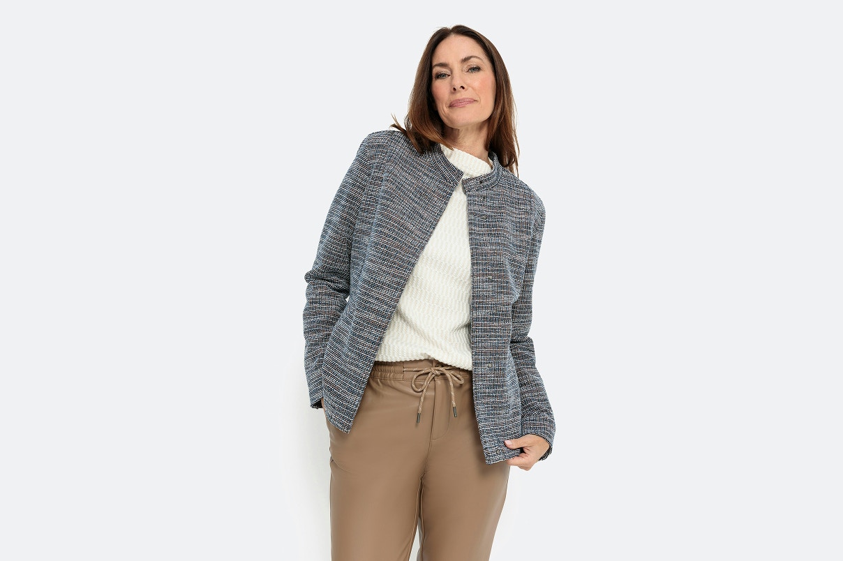 Eine Frau im Bonita Bouclé Blazer mit weißem Shirt und beiger Fake-Lederhose.   