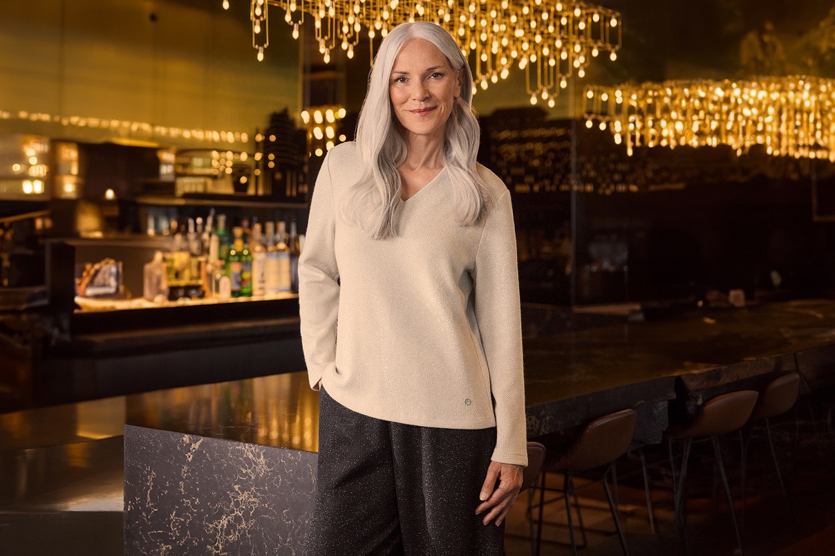 Een vrouw in een beige Bonita glittertrui. 