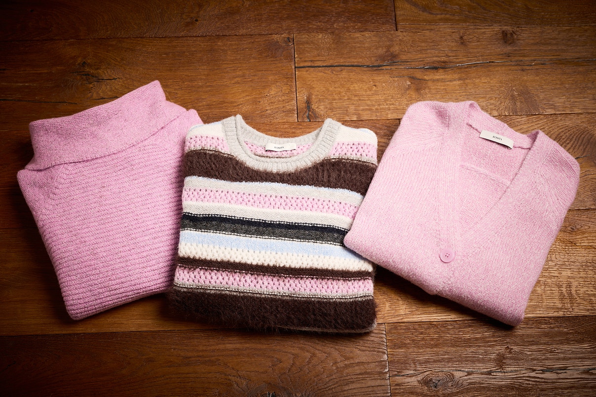 Drei Bonita Pullover liegend auf einem Holzboden. 