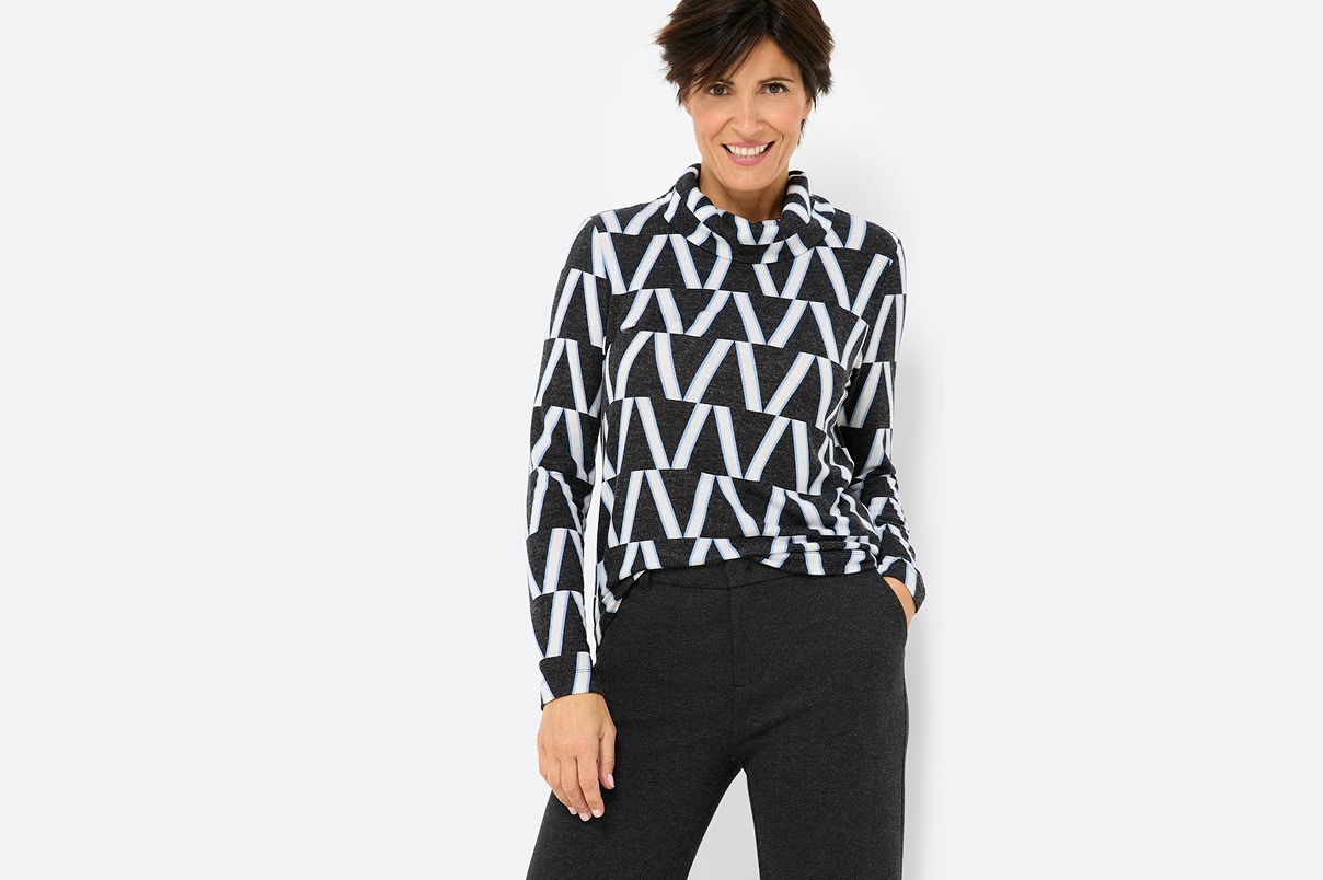 Eine Frau in Bonita Neuheiten, in einem Strickpullover und grauer Stoffhose. 