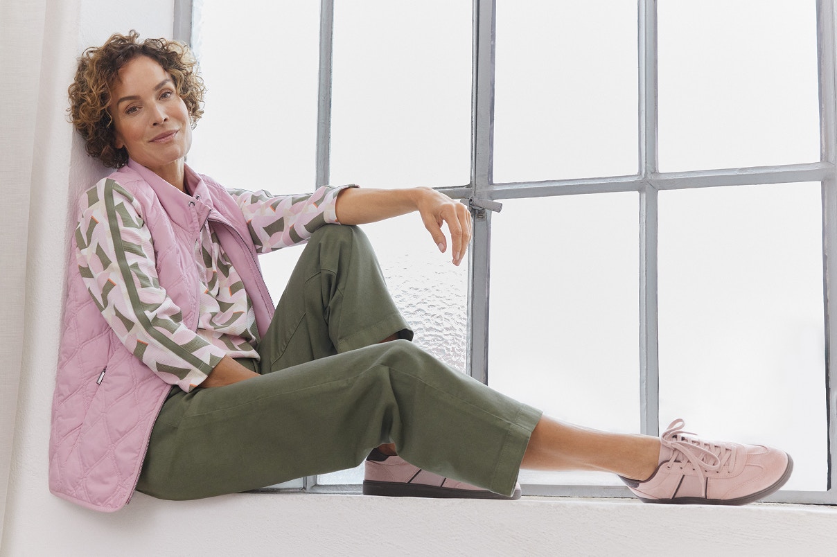 Eine Frau sitzend auf einer Fensterbank in Bonita Neuheiten. 