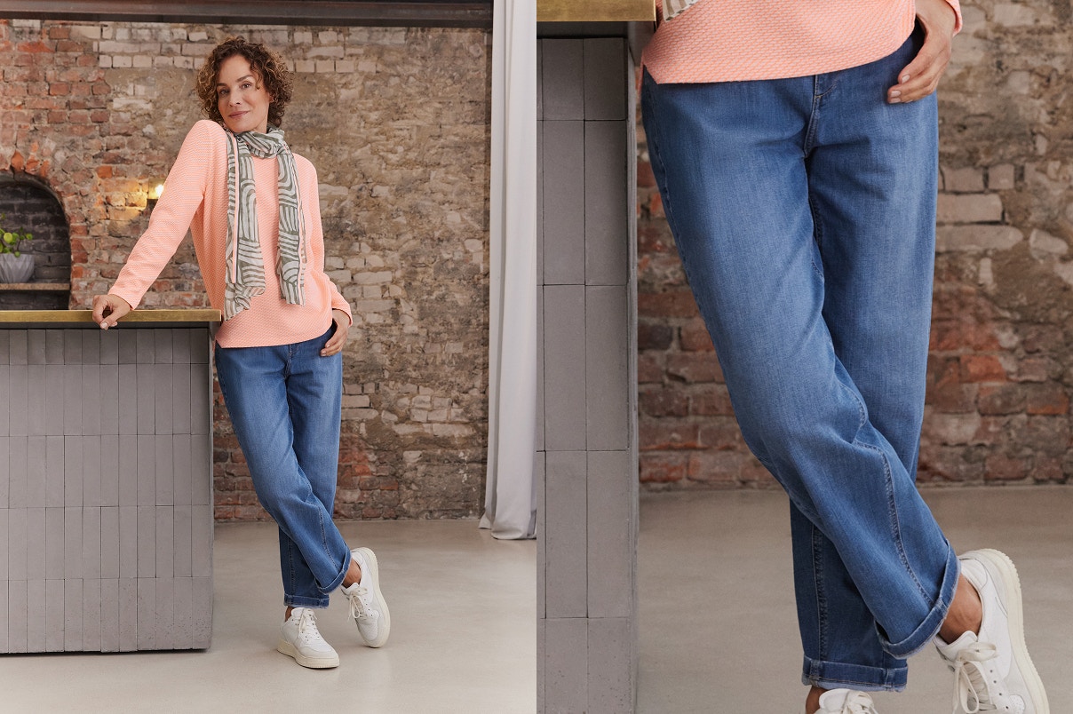 Een vrouw staand in een blauwe Bonita-jeans met trui en sjaal. 