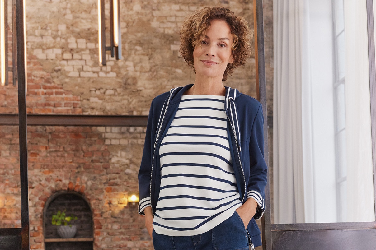 Een vrouw in jeans en gestreept shirt met bijpassend sweatshirtjack.
