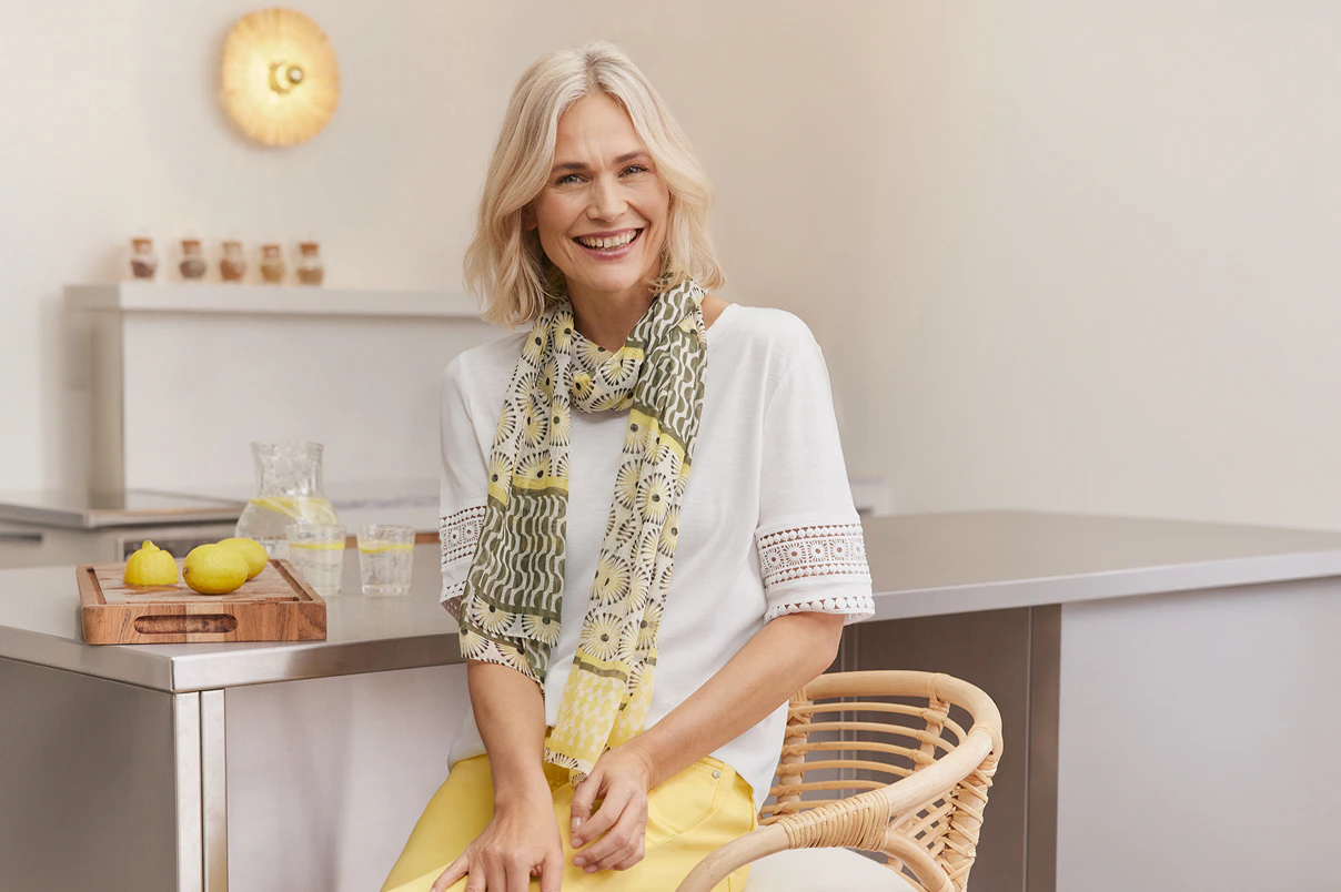 A woman wearing yellow jeans, a white shirt, and a matching Bonita scarf.