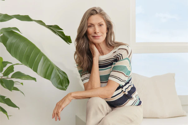 Eine Frau in beiger Hose und einem gestreiften Strickpullover. 