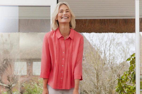 Een vrouw in een beige broek en een gekleurde linnen blouse. 
