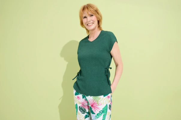 Eine Frau in grünem Shirt und geblümter Hose. 