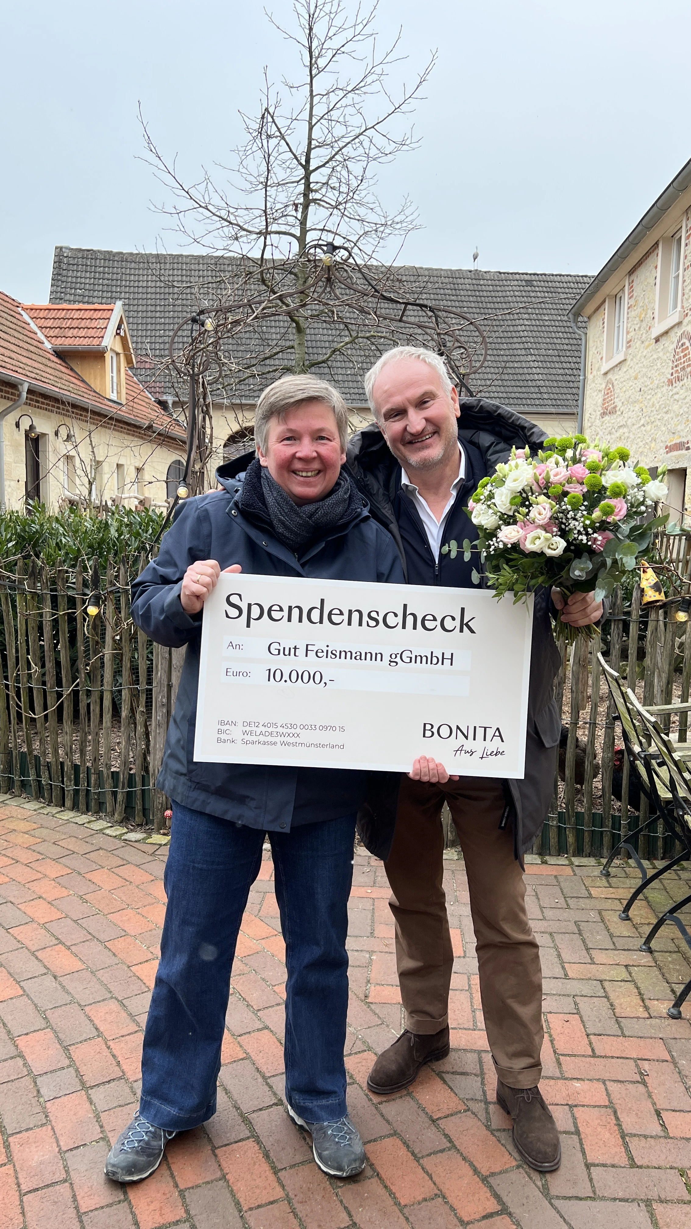 De directeur van Bonita en Carolin Feismann overhandigen op het terrein van Gut Feismann een donatiecheque van 10.000 euro aan het kinderhospice.