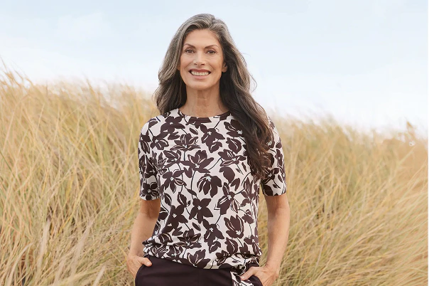 Een vrouw in een bruine broek en een shirt met een patroon.