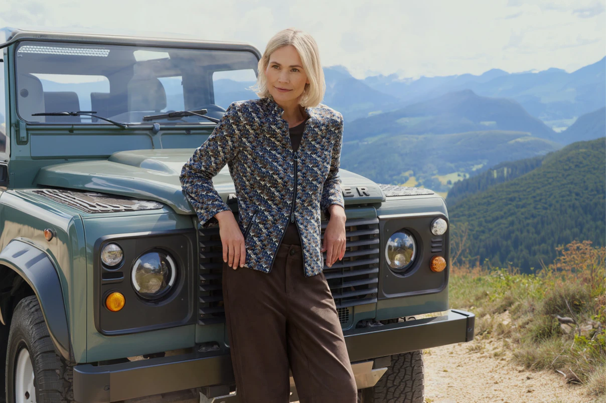Eine Frau in brauner Hose mit einem gemusterten Blazer.  