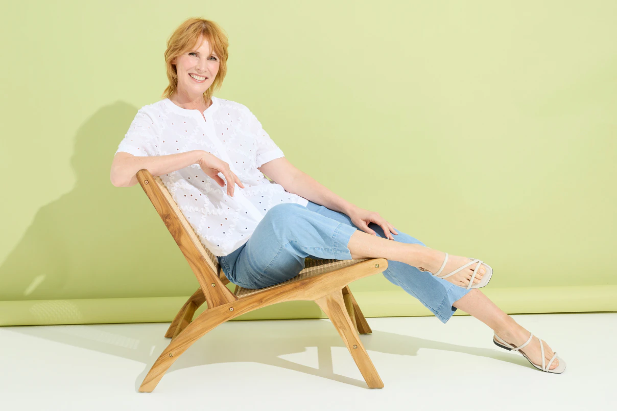 Eine Frau in Jeanshose und weißer Bluse mit Stickerei.  