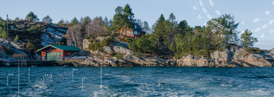Felsige Küstenlandschaft mit roten Holzhäusern, grünen Bäumen und blauem Meer als Motiv der CASAMODA Herrenkollektion.