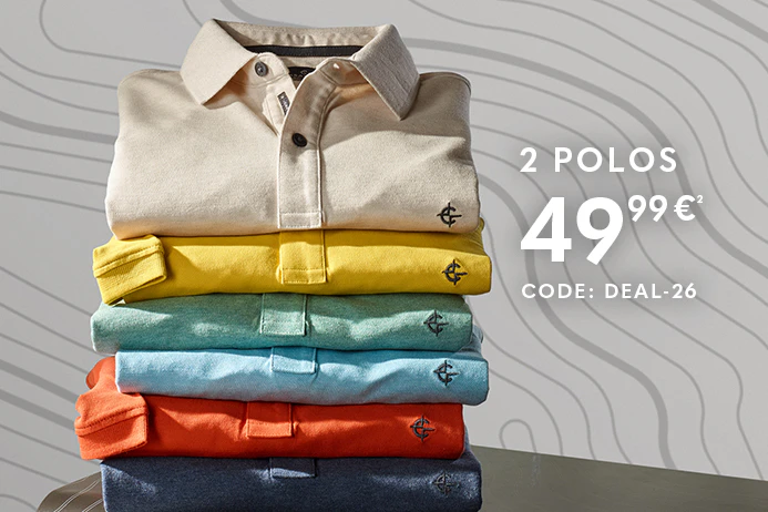 Mehrere gefaltete Poloshirts in verschiedenen Farben sind übereinander gestapelt. Rechts daneben steht ein Kompass auf einem Koffer, der Hintergrund besteht aus einer hellen Wand.
