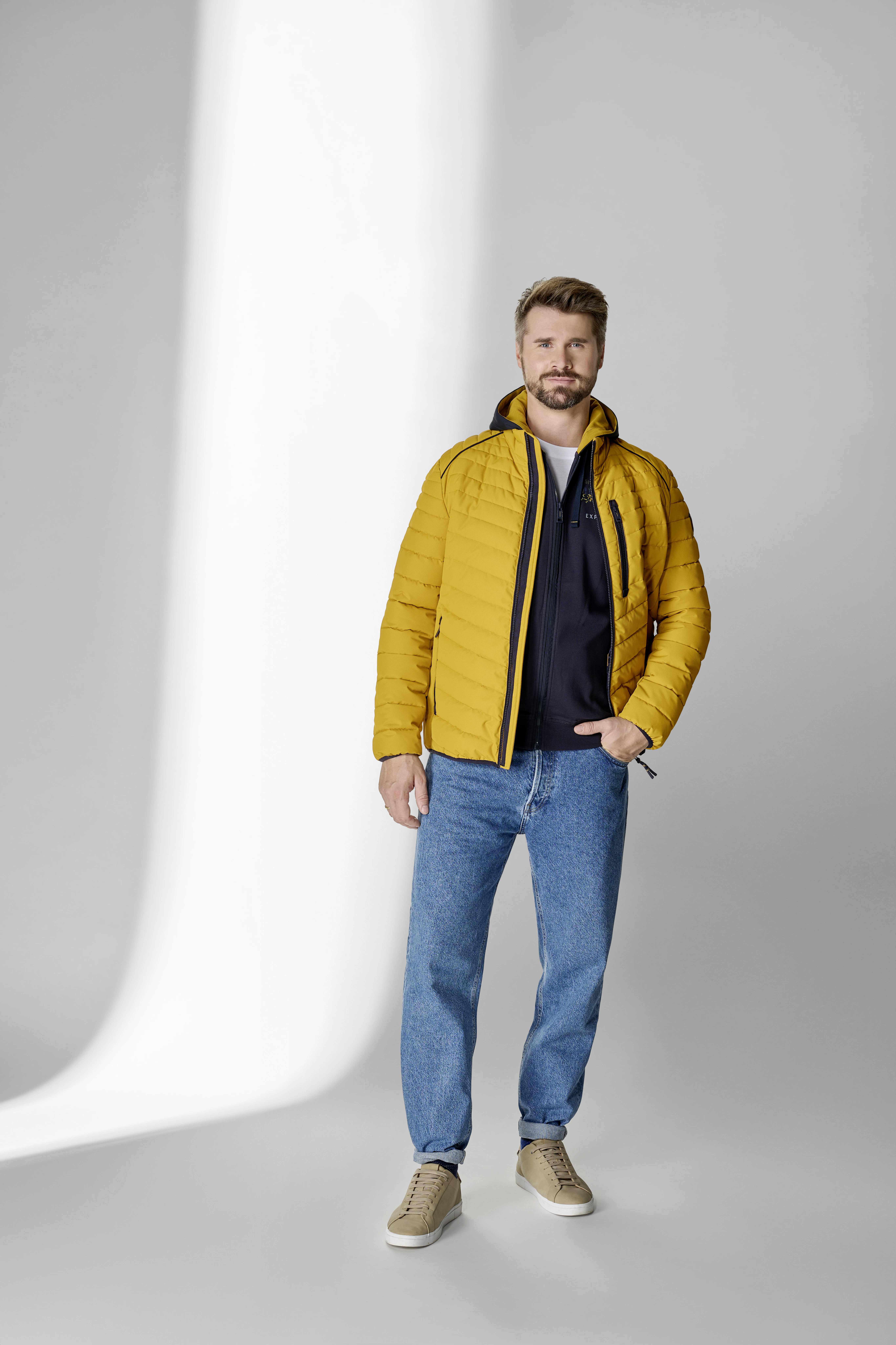Thore Schölermann posiert mit einer gelben Jacke von CASAMODA