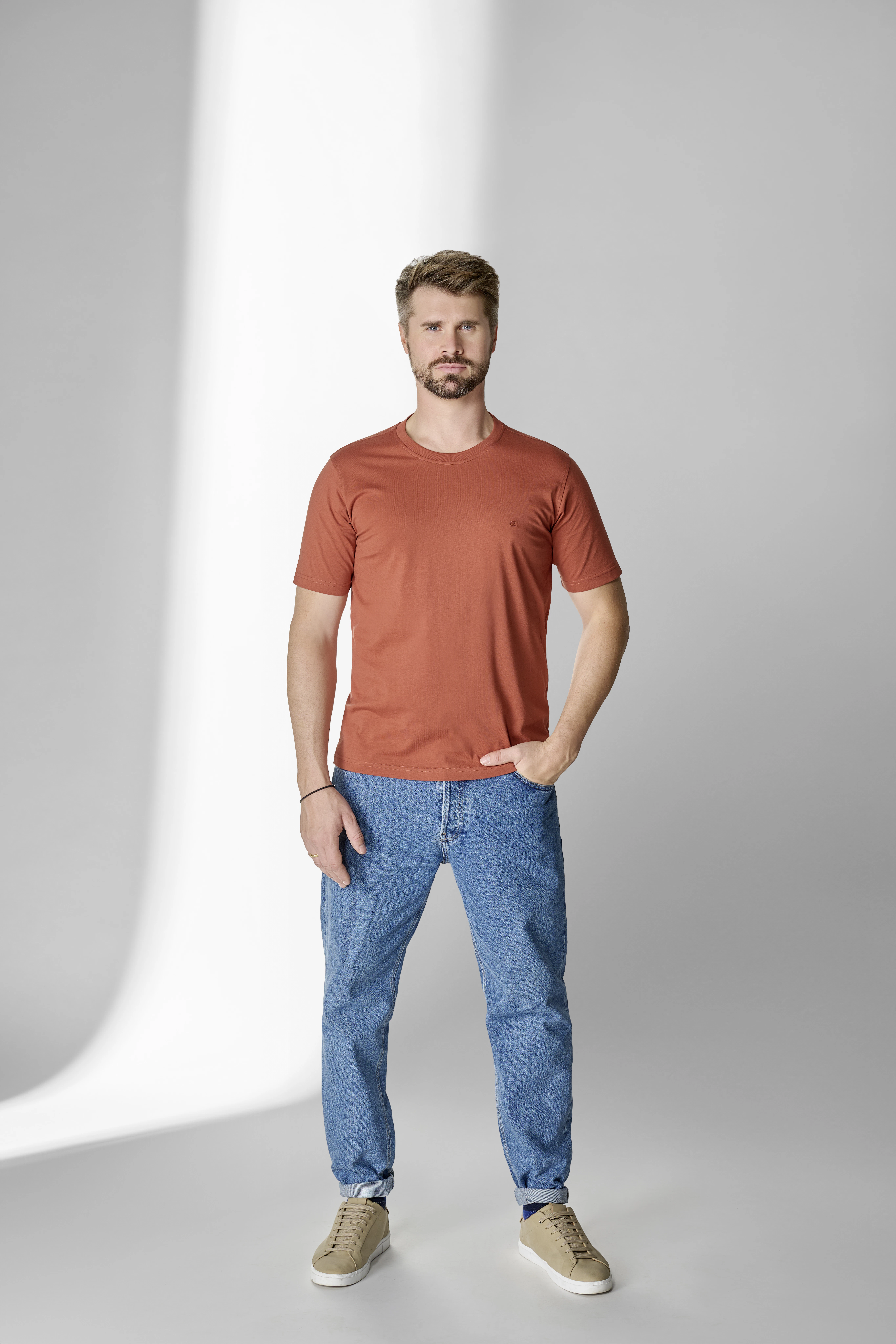 Thore Schölermann posiert mit einem orangenen T-Shirt von CASAMODA