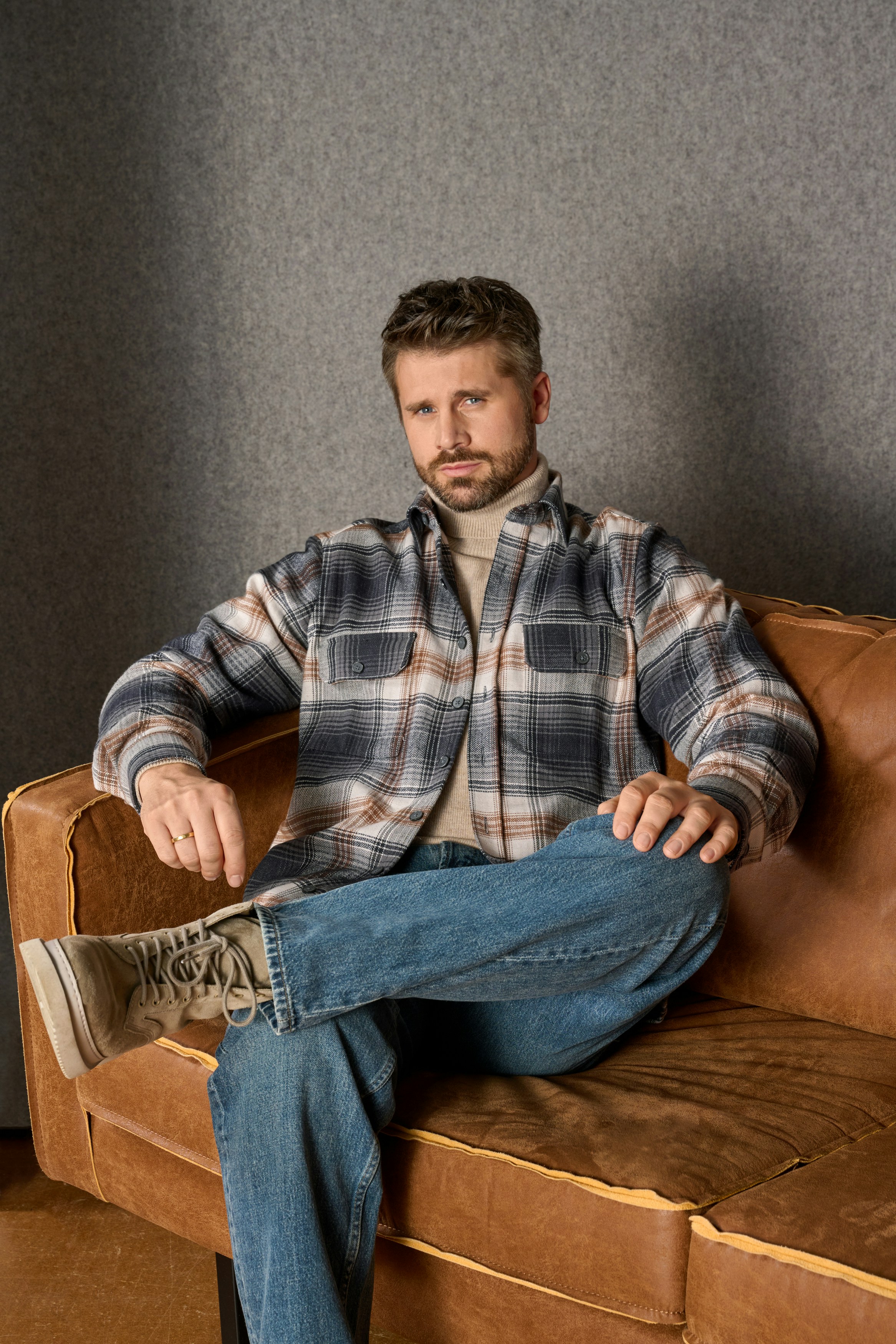 Thore Schölermann sitzt auf einem Sessel mit einem karierten Overshirt