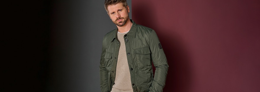 Thore Schölermann posiert vor einem Haus mit einer grünen Overshirtjacke von CASAMODA.