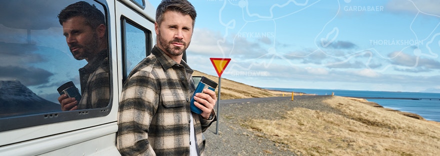 Thore Schölermann posiert neben einem weißen Auto mit einem gelben karierten Overshirt von CASAMODA