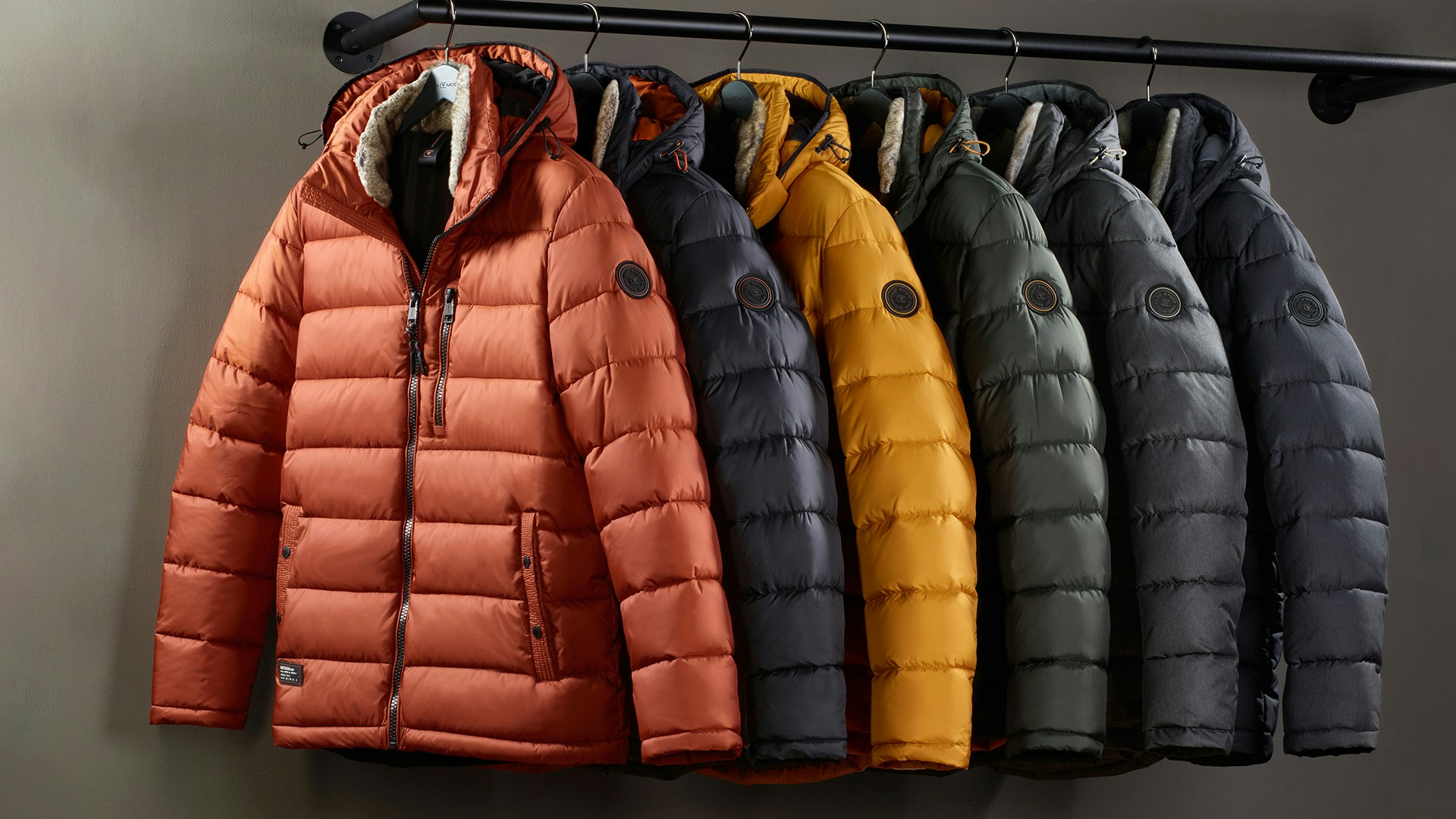 Sechs Casamoda Steppjacken in Herbstfarben hängen an einer schwarzen Kleiderstange