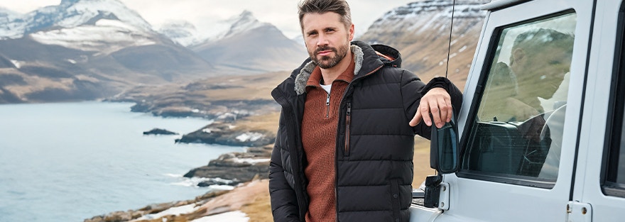 Thore Schölermann in Casamoda Jacke am Jeep mit Bergkulisse im Hintergrund