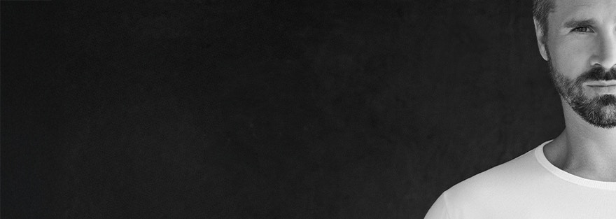 Thore Schölermann in einem weißen T-Shirt von CASAMODA mit schwarzem Overlayer