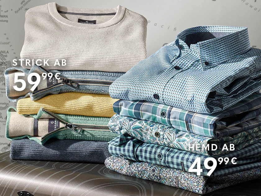 Gestapelte Oberteile und Hemden in verschiedenen Farben und Mustern liegen auf einem Koffer. Im Hintergrund ist eine Weltkarte zu sehen.