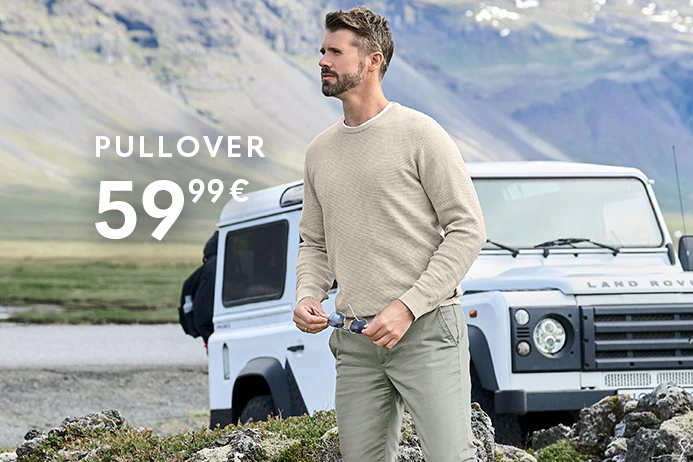 Thore Schölermann steht vor einem weißen Geländewagen in bergiger Landschaft und hält eine Sonnenbrille in der Hand