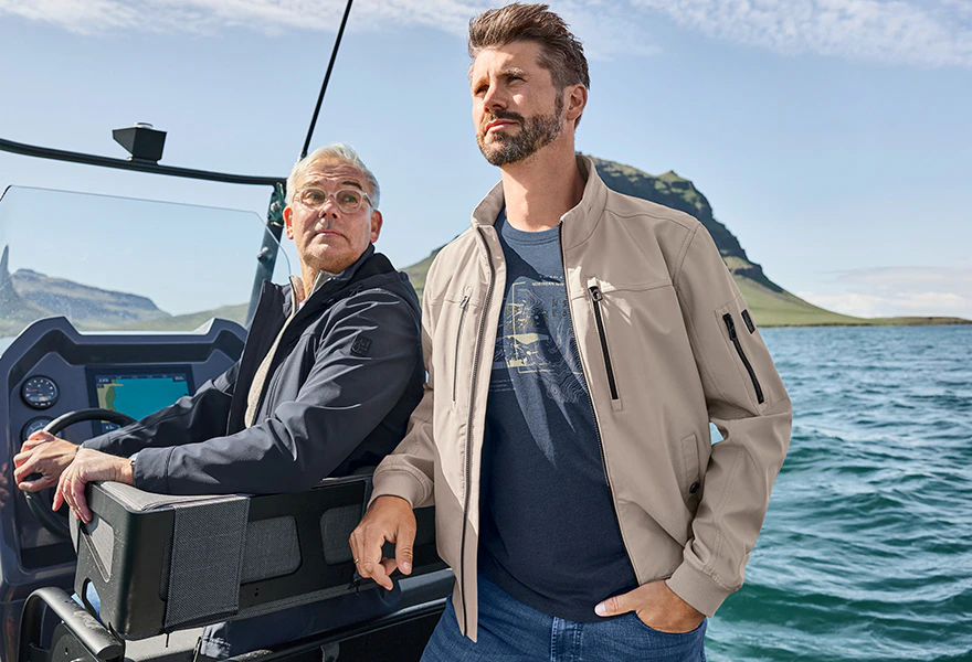 Zwei Männer in einem Jeep, Mann im hellen Blouson und Mann in blauer Jacke