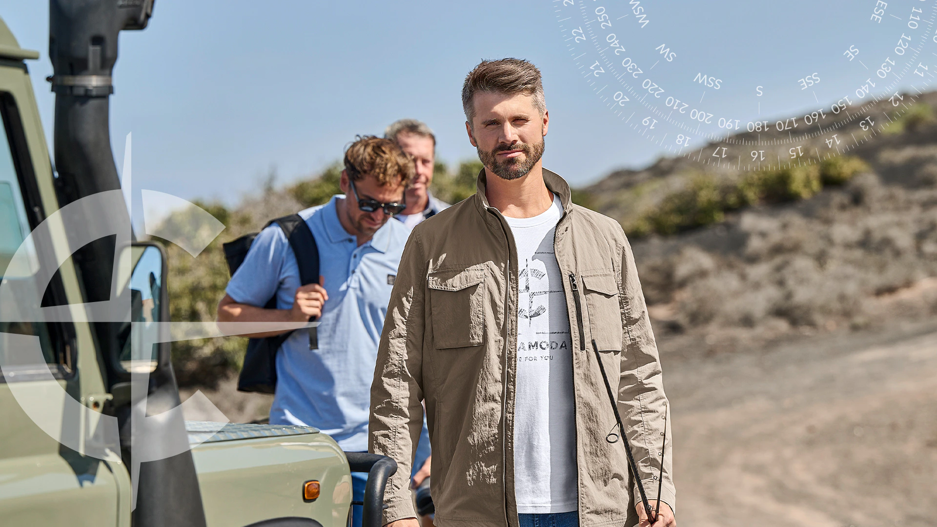 Herren Leichtjacke in Beige über Print-T-Shirt und Jeans bei einem Outdoor-Ausflug mit Geländewagen