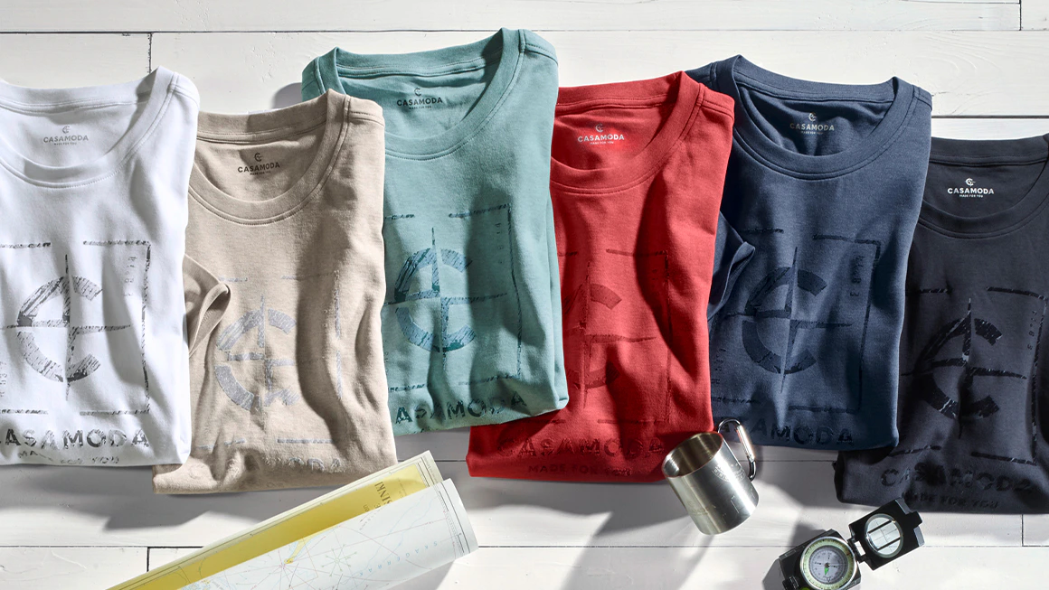 CASAMODA Herren T-Shirts mit CASAMODA Logo Print in vielen Farben dekorativ auf hellem Holzhintergrund