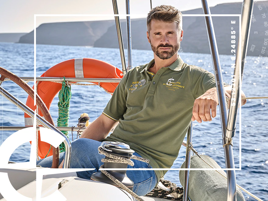 Herren Poloshirt in Oliv mit Logo-Print auf einem Segelboot vor dem Meer