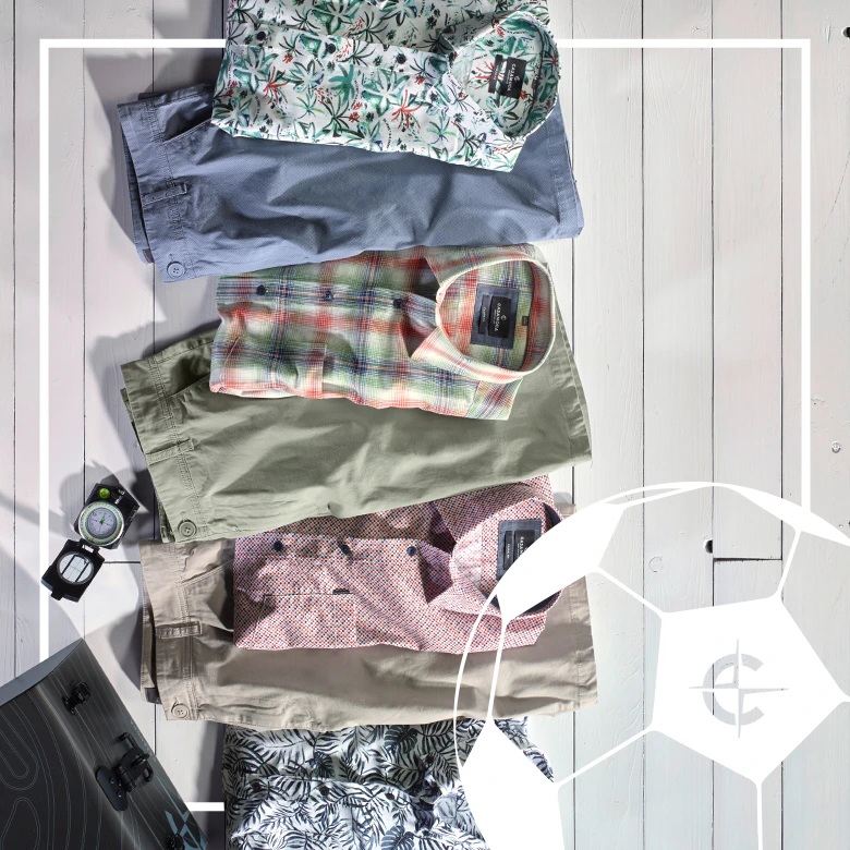 Sommerliche CASAMODA Herrenoutfits mit Hemden und Shorts auf weißem Holzboden mit Kompass