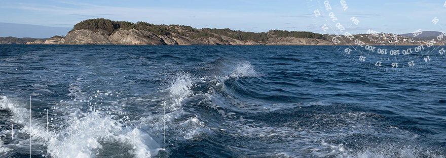 Aufgewühltes Meer vor einer felsigen Küstenlandschaft mit kleinen Inseln am Horizont.