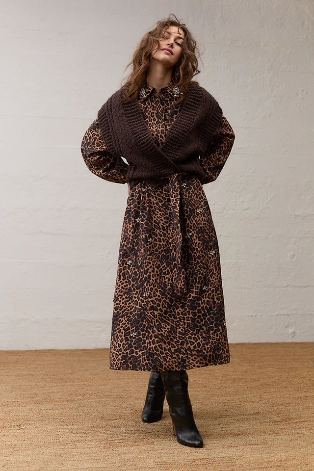 The model is wearing a leopard-print dress with rhinestone embellishments and a brown slipover.